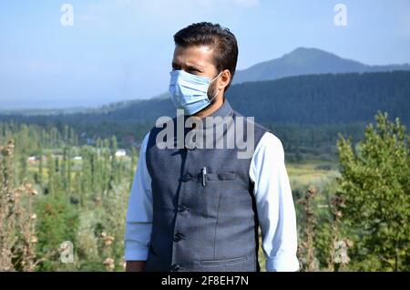 Asian Man wearing mask is talking on phone at a beautiful place after coronavirus lockdown. Stock Photo