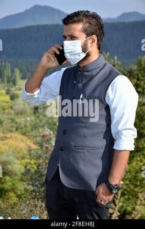 Asian Man wearing mask is talking on phone at a beautiful place after coronavirus lockdown. Stock Photo