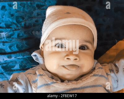 Smiling kid photographs at home under blanket looks beautiful. Digital and 4k photos of child. Stock Photo