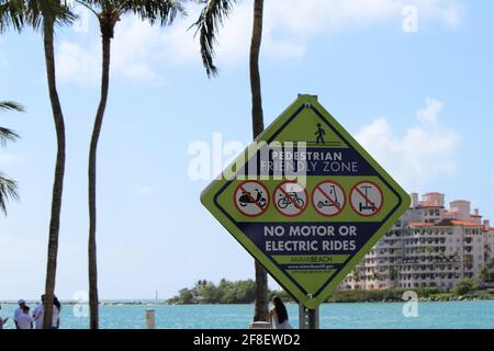 USA: Pedestrian friendly zone sign, no motor or electric rides at South Pointe beach in Miami Beach, Florida with a view of Palazzo Del Sol condominium Stock Photo