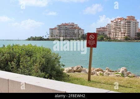 Sign to keep away from storm sewer at South Pointe beach in Miami Beach Florida with a background view of Palazzo Del Sol condominiums in Fisher Island Stock Photo