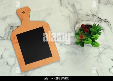 Flat lay of cutting board and flower pot on marble surface Stock Photo