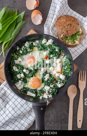 Green shakshuka. Fried eggs with wild garlic and feta cheese Stock Photo