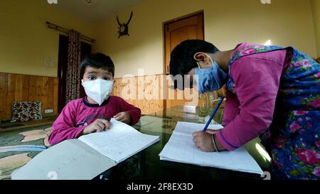 Masked students  reading and writing their school work at home during the pandemic coronavirus. Online classes are common due to covid 19.