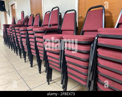 Stack of red and black chairs in a room used for meetings and conferences. Stock Photo