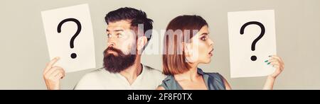 Portrait of couple holding paper question mark. Couple thinking about something. Confused couples with question marks. Conflict between two people Stock Photo