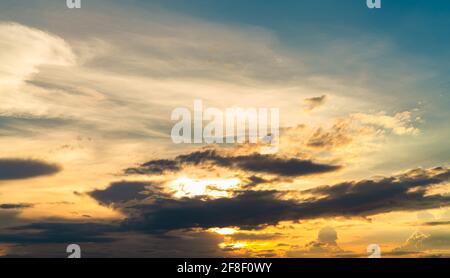 Beautiful sunset sky. Golden sunset sky with beautiful pattern of clouds. Yellow, blue and dark clouds at sunset time. Freedom and calm background. Stock Photo