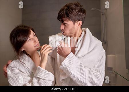 young couple in love brushing teeth in bathroom - concept of complicity and couple life Stock Photo