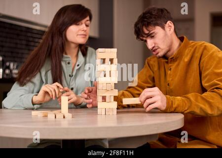 company of young people plays table game jenga. friends in a good mood at home Stock Photo