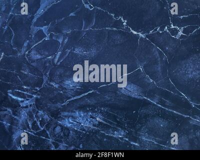 Texture of navy blue marble with lines of pattern, macro background. Dark azure stone backdrop from mineral tile, closeup. Stock Photo