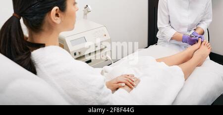 Laser treatment of onychomycosis. Woman gets laser treatment fungal infection on toenail and onychomycosis treatment with a medical laser Stock Photo