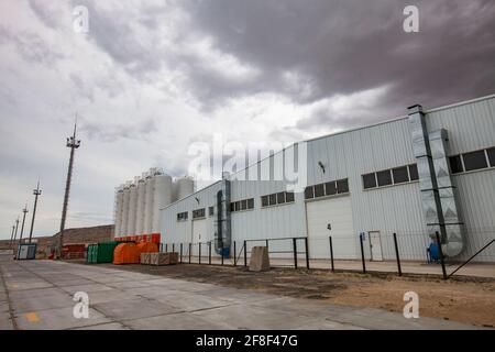 Mangystau, Kazakhstan: Bautino bay. Loading terminal on Caspian sea. Storage tanks, industrial building (warehouse). Grey storm clouds. Stock Photo