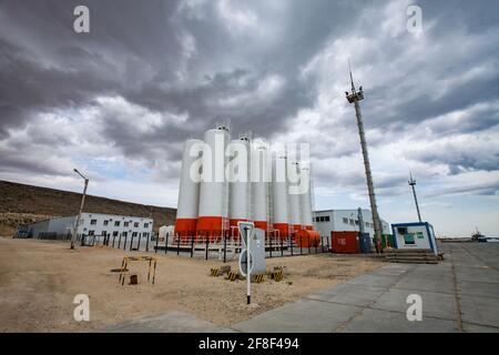 Mangystau, Kazakhstan: Bautino bay. Loading terminal and warehouse on Caspian sea. Storage tanks on sky with grey storm clouds. Stock Photo