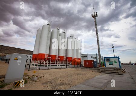 Mangystau, Kazakhstan - May 19 2012: Bautino bay. Oil loading terminal on Caspian sea. Storage tanks and mast. Grey storm clouds. Stock Photo