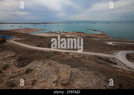 Bautino bay, Mangystau, Caspian sea, Kazakhstan. White serpentine road down to sea and oil loading terminal. Tanker ships on horizon. Stock Photo