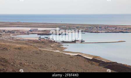 Bautino bay, Caspian sea, Mangystau,Kazakhstan. Oil tanker ship Bautino seaport and township. Stone pier in water. Panorama view. Stock Photo