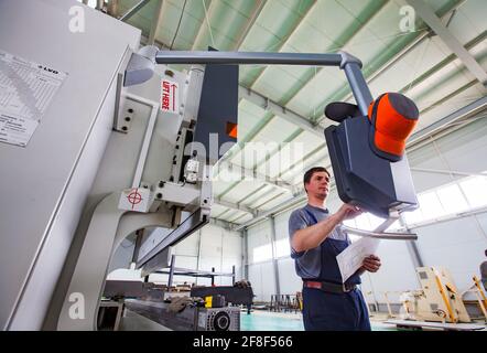 Aktau, Kazakhstan. Young operator programming CNC machine LVD. Production of special electric equipment. RIG Ltd Stock Photo