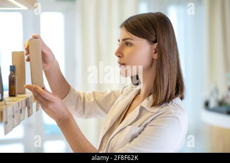 Pretty shop assistant examining new products and looking involved Stock Photo