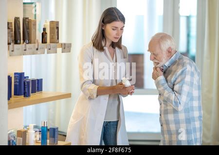 Perfumer Assistant Young shop assistant in perfume shop showing a new fragrance to a ...