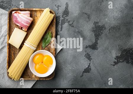 Ingredients for making pasta alla carbonara prosciutto, raw pasta, on gray stone background, top view flat lay, with copy space for text Stock Photo