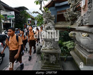 Balinese school children walking by the Sarasvati temple in Ubud, Bali, Indonesia. Stock Photo