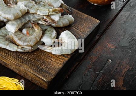 Raw tiger prawns, on wooden cutting board, on old dark wooden table , with copy space for text Stock Photo