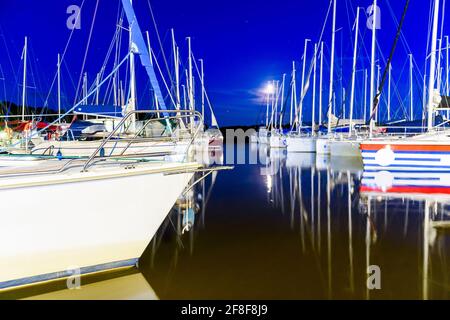 Yachts moored in a harbor at night. Sailboats in the dock. Summer vacations, cruise, recreation, sport, regatta, leisure activity, service, tourism Stock Photo