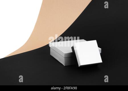mock-up of two closed boxes in silver and black on a background of beige, black, white paper Stock Photo