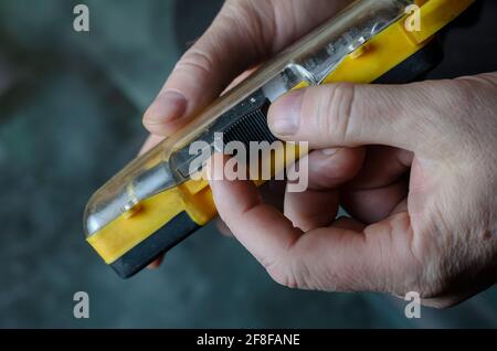 A man is holding a yellow and black box of screwdriver bits. Close-up of a man's hand with a plastic box of hand tools. Adult male, Caucasian. Inside Stock Photo