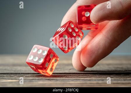 The hand is throwing red dices on the wooden table. The concept of a casino and a lucky chance to win Stock Photo