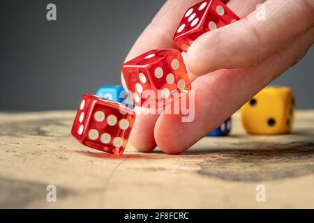 The hand is throwing the red dices on the map. The concept of board games and a lucky chance to win Stock Photo