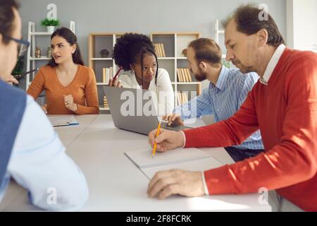 Group of diverse business people discussing their projects sitting at office table together Stock Photo
