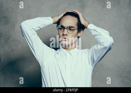 fashionable guy with curly hair gesturing with his hands on a gray background portrait close-up Stock Photo