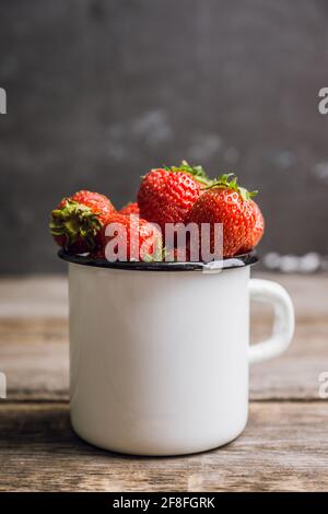 Ripe and juicy strawberries in old rustic metal cup. Selective focus. Shallow depth of field.