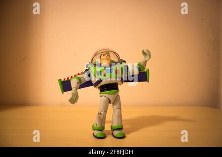 AVOLA, ITALY - Mar 22, 2021: View of the original toy Buzz Lightyear from the action movie Toy Story, standing upright on a wooden table and with it l Stock Photo