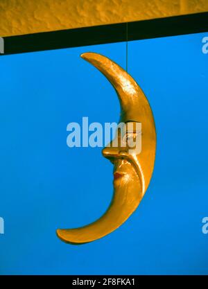 The Man in the Moon. Domestic ornament, gold coloured wooden crecent moon with eyes, nose and mouth. Stock Photo