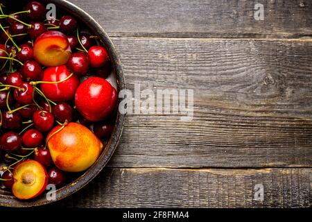 Ripe plums, nectarines and cherries in rustic pan. Selective focus. Stock Photo