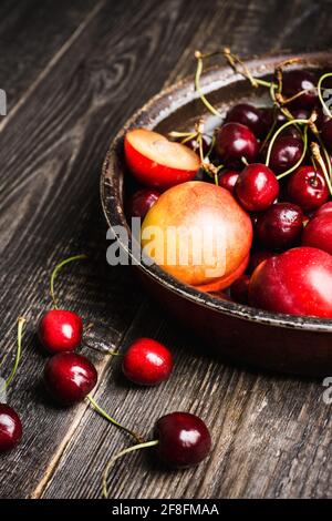 Ripe plums, nectarines and cherries in rustic pan. Selective focus. Stock Photo