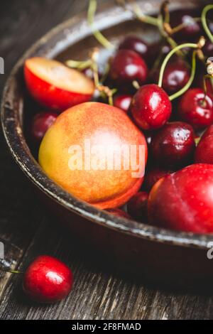 Ripe plums, nectarines and cherries in rustic pan. Selective focus. Stock Photo