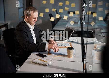 Cheerful businessman is doing paperwork in office Stock Photo