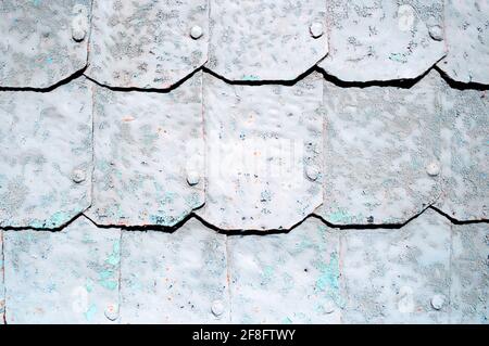 Metal background with hammered metal plates with rivets on the metal surface covered with grey peeling paint Stock Photo