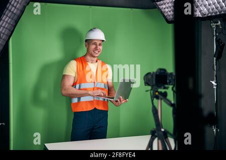 Joyful male builder using laptop and recording video Stock Photo