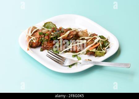 Chilli paneer or Spicy cottage cheese, Garnish with capsicum, onion, cabbage and spring onion, favourite indian starter menu, served in white Dish, Stock Photo