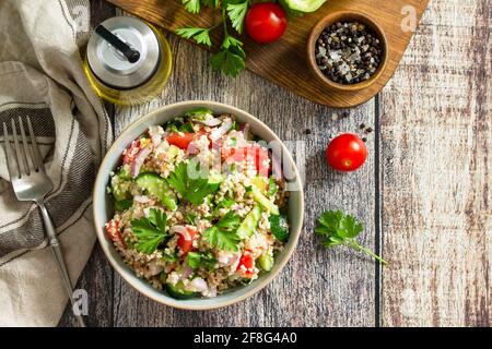 Food dieting concept, tuna salad. Couscous salad with conserved tuna, tomatoes, cucumbers and purple onions on rustic wooden table. Top view flat lay. Stock Photo