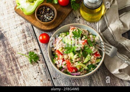 Food dieting concept, tuna salad. Couscous salad with conserved tuna, tomatoes, cucumbers and purple onions on rustic wooden table. Stock Photo