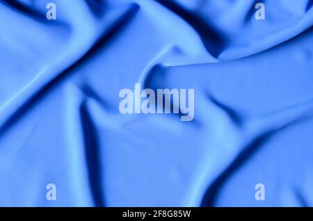 The background is made of a delicate blue chiffon fabric with folds in the form of waves. Top view. Selective focus. Stock Photo