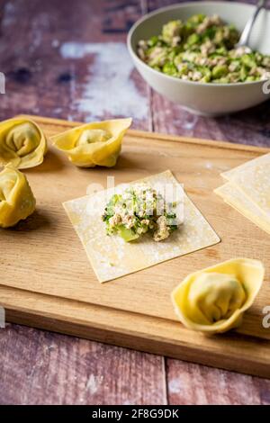 Folding instructions of vegan wonton dumplings with tofu and broccoli on wooden cutting board, side view Stock Photo