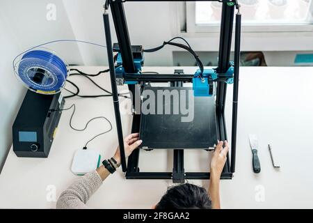 Stock photo of unrecognized technician fixing modern 3d printer. Stock Photo