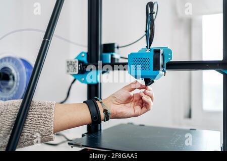 Stock photo of unrecognized technician fixing modern 3d printer. Stock Photo
