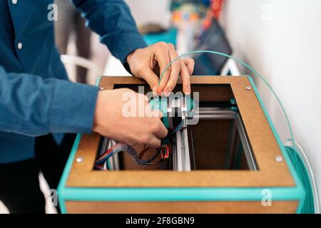 Stock photo of unrecognized technician fixing modern 3d printer. Stock Photo